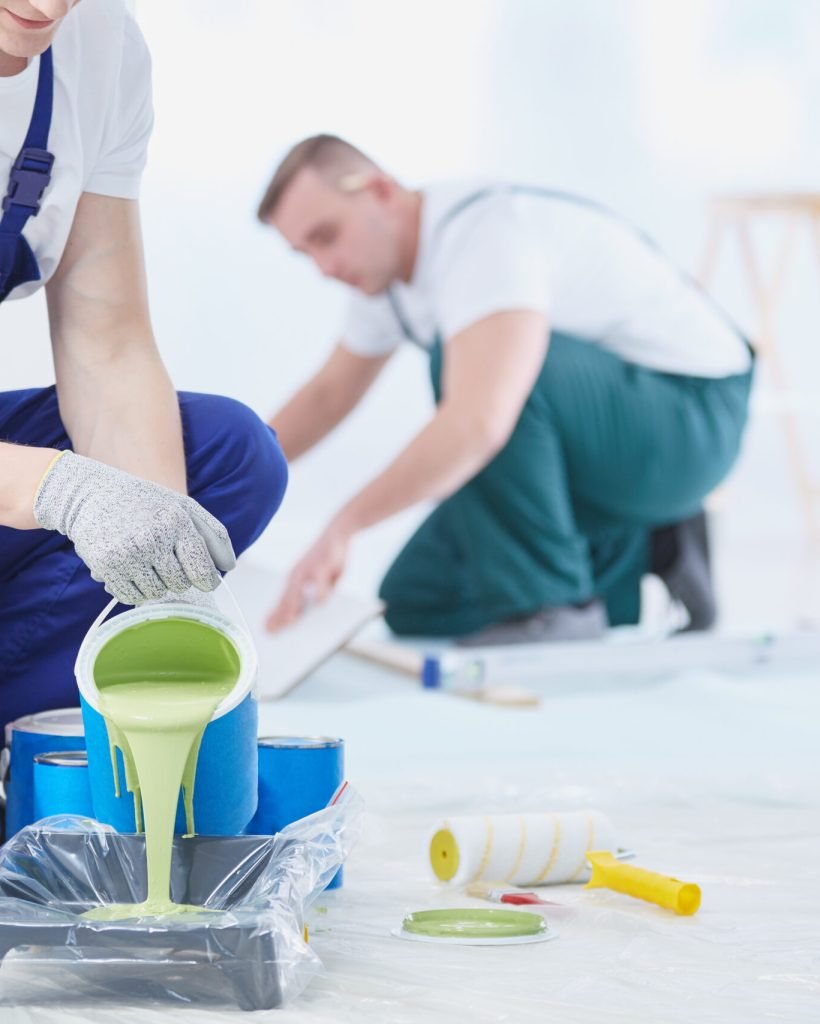 Professional interior construction worker pouring green color to paint