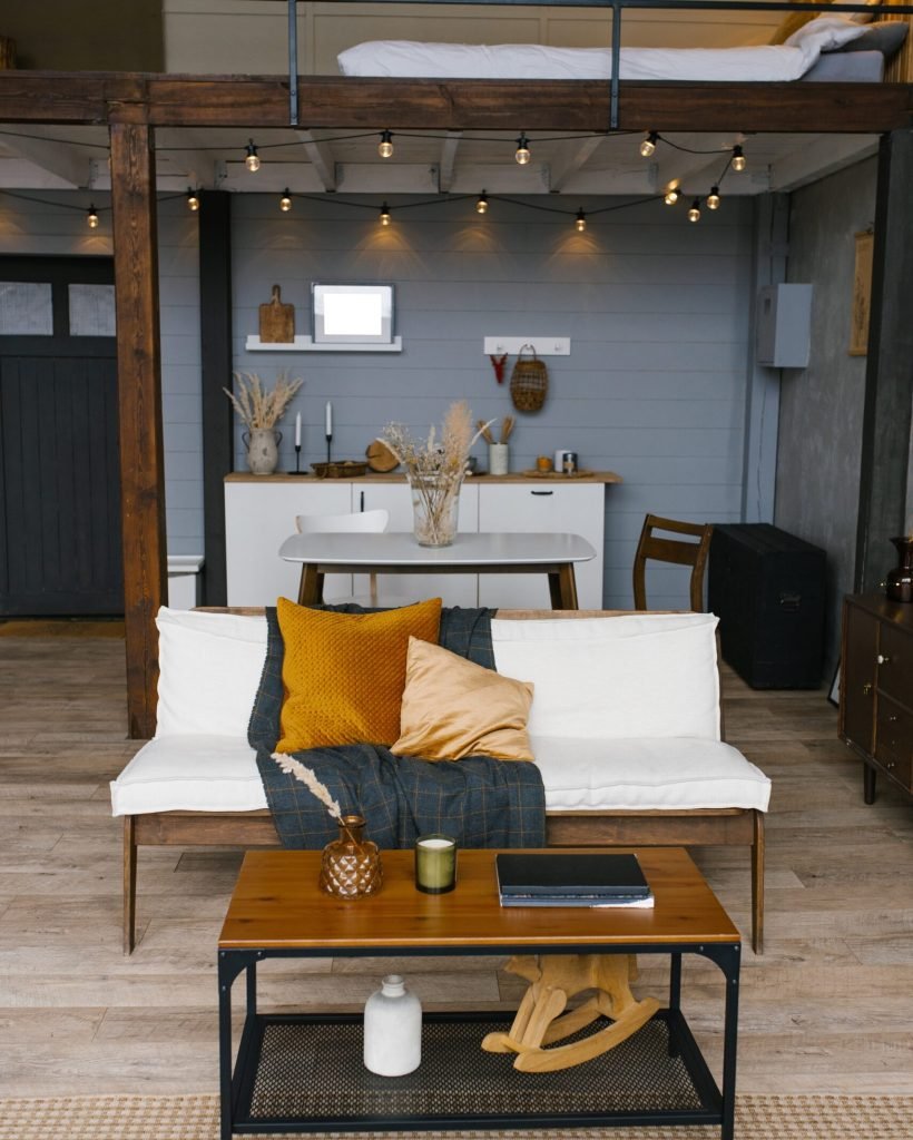 The Scandinavian-style interior of the dining room, sofa and coffee table against the background of the kitchen in gray and mustard colors
